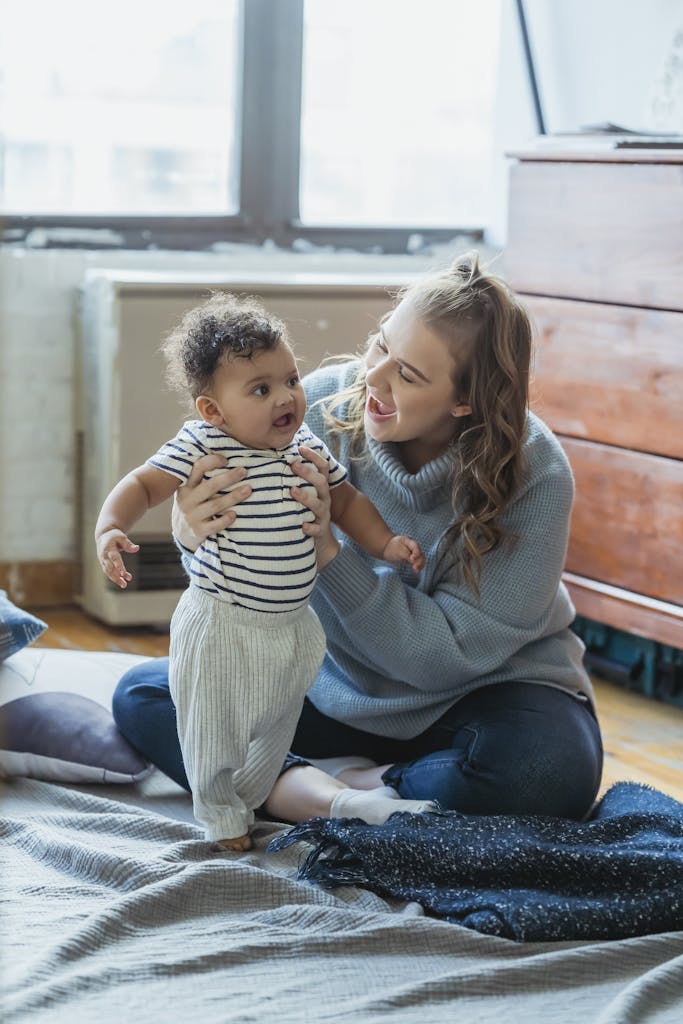 Cheerful mother hugging and playing with cute ethnic baby